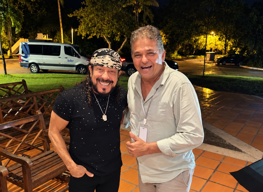 Edson Vasconcelos Carvalho ao lado do cantor Bell Marques, com uma van da EVC Turismo ao fundo